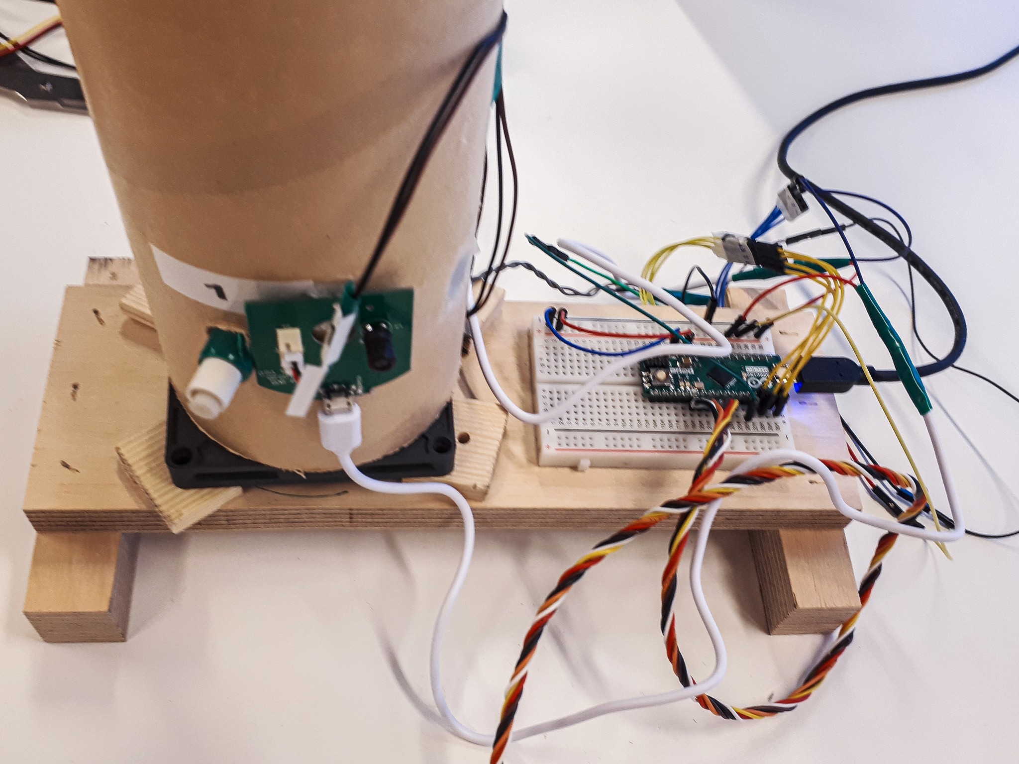 a view from the top on the Scentony device with multiple wires, hard cardboard funneling system and Arduino Micro board. All mounted to a wooden base