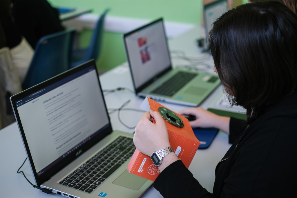 Close-up of a student using the Arduino Explore IoT Kit and keyboards on a desk during usability testing session