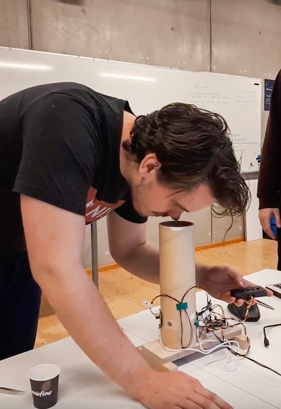a picture of a male user testing the Scentony device bending to smell the fragrance coming out of the funneling system tube